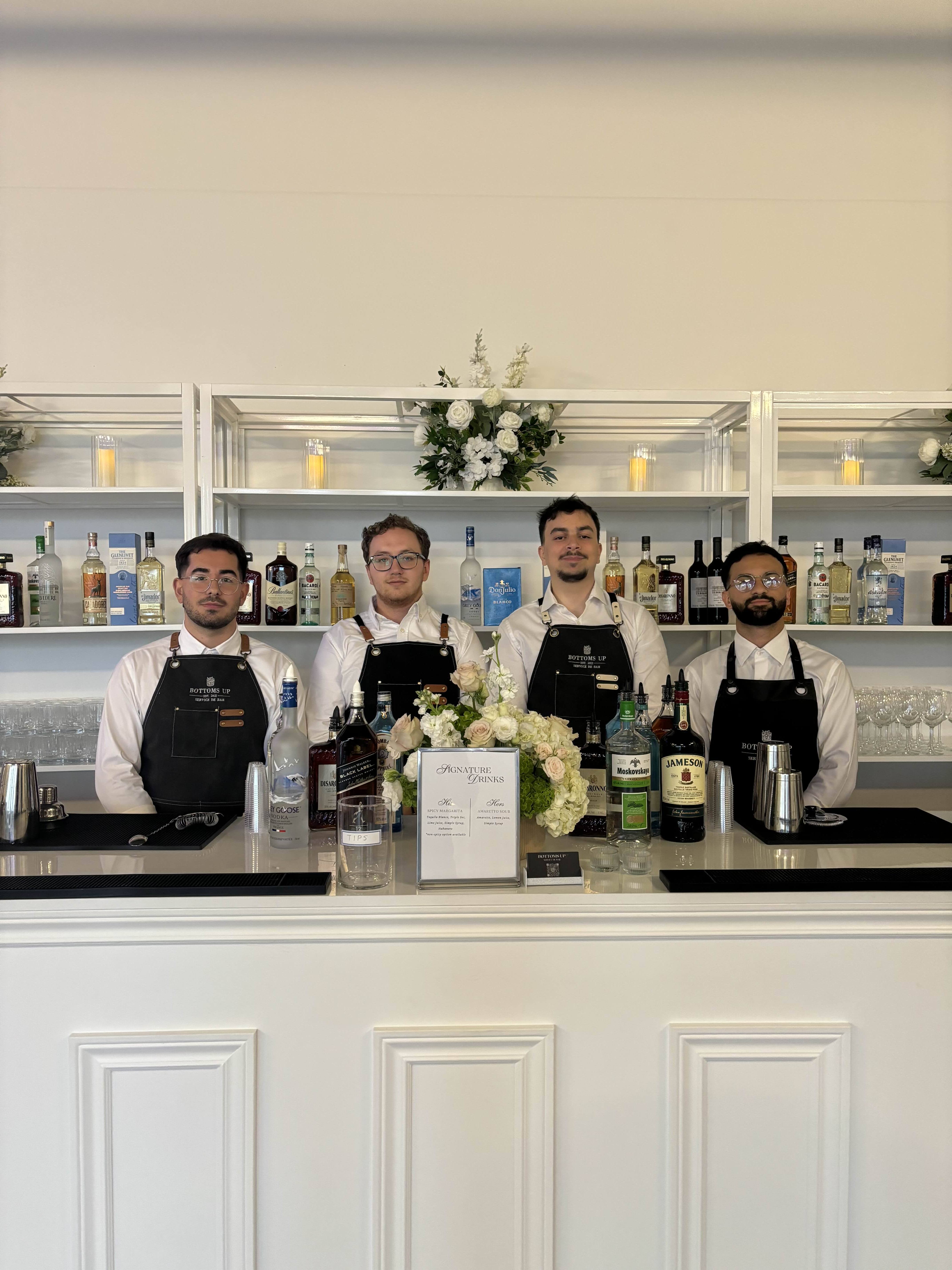 Professional bartender team at elegant white bar